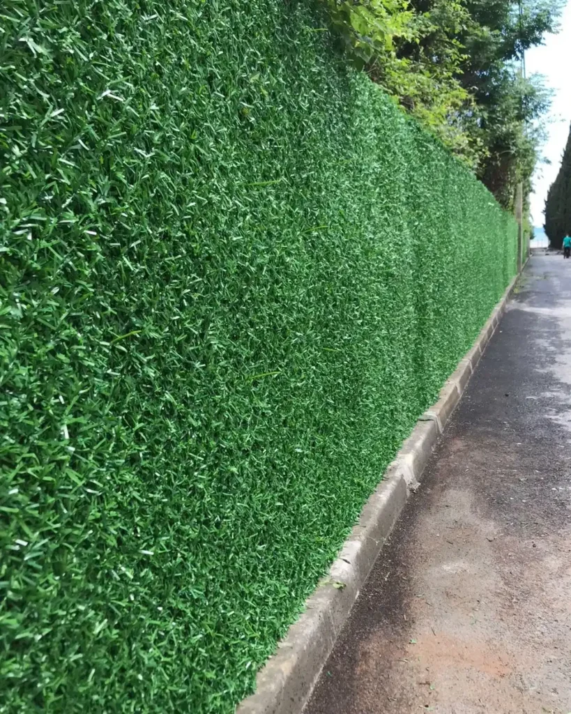 Світло зелений декоративний паркан із штучної хвої на сітці рабиця вздовж дороги