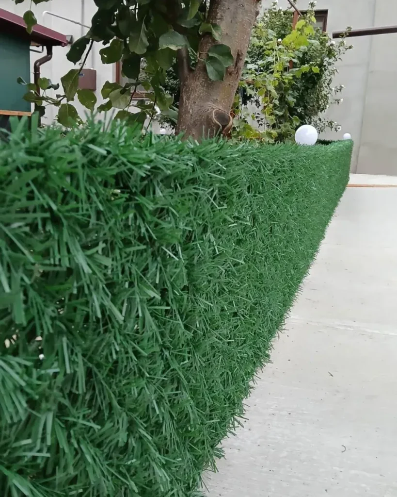 Світло зелений паркан із штучної хвої на металевій сітці рабиця біля будинку