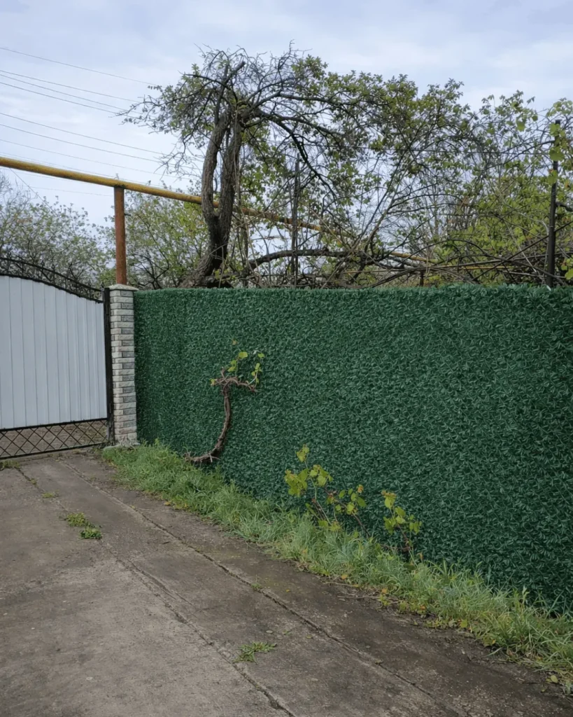 Темно зелений декоративний паркан на сітці рабиця вздовж дороги